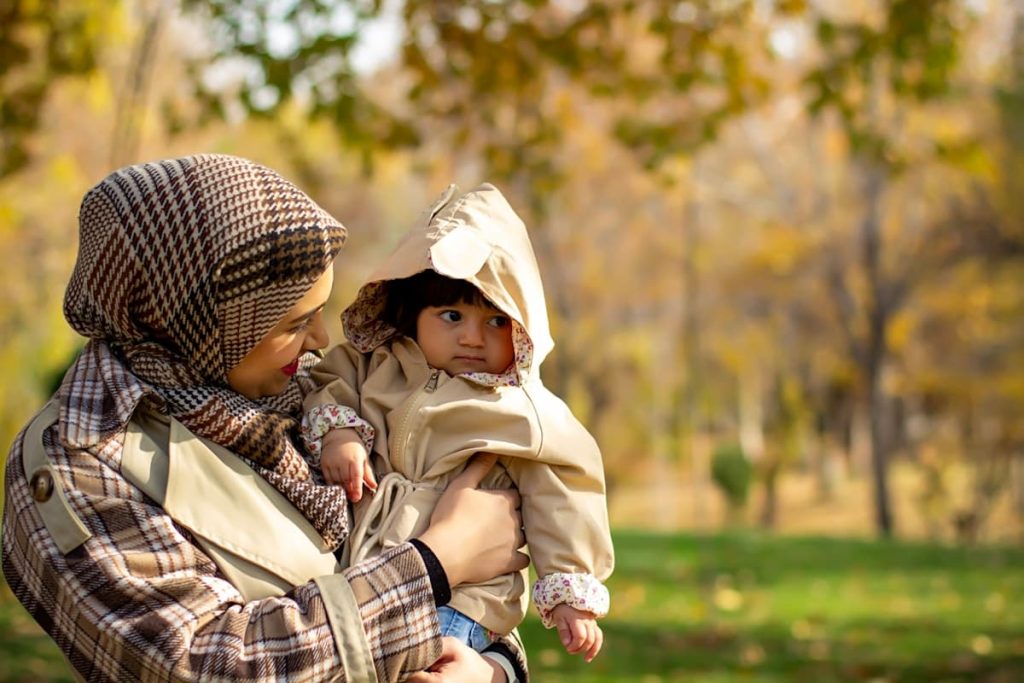 أم تحضن طفلها في الحديقة — تعبير عن الأمومة الدافئة