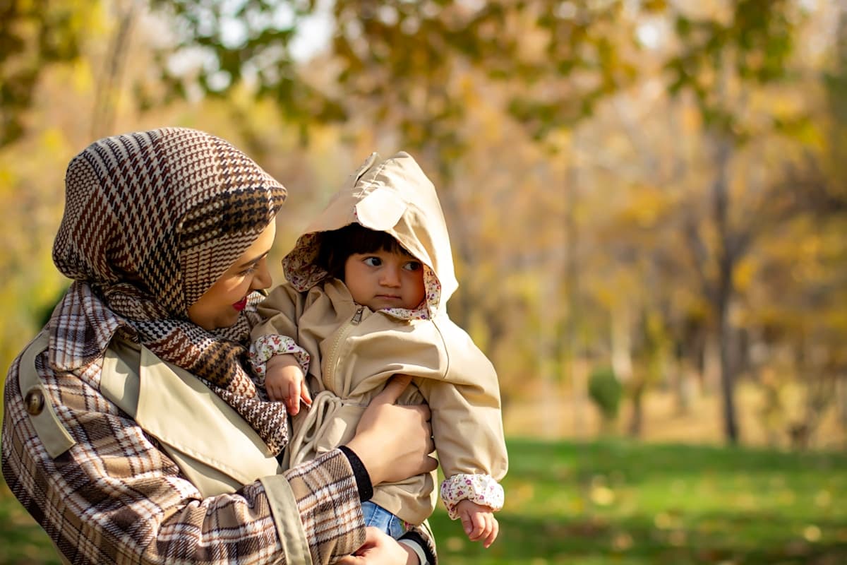أم تحضن طفلها في الحديقة — تعبير عن الأمومة الدافئة